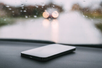 Smart phone on car dashboard on rainy day