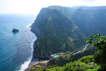 Papier Peint photo autocollant Atlantic Ocean Road Winding road leading down to a bathing complex with outdoor swimming pool in Sao Jorge on the north coast of Madeira island (Portugal) in the Atlantic Ocean