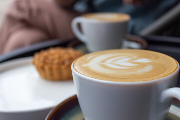 Close-up of a latte with artful foam design served with a sweet pastry