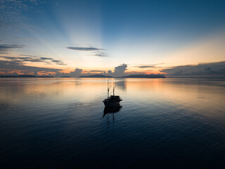 A phinisi schooner, used as a diving liveaboard boat, is silhouetted at sunrise in Raja Ampat,...