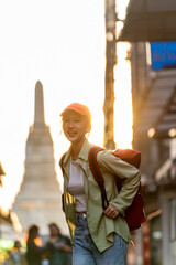 Asian Woman Traveler Posing Against the Sunset Moment of Wat Arun - The Temple of Dawn in Bangkok...