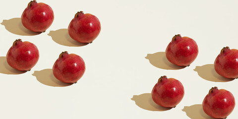 Isolated pomegranate fruits laid out against a beige background. Copy space, minimal food concept. Healthy nutrition. Copy space.