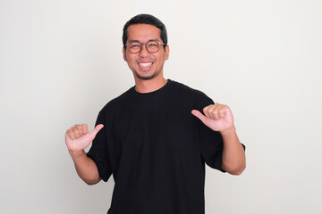 Fototapeta premium Adult Asian man pointing to plain black t-shirt that he wearing with happy expression