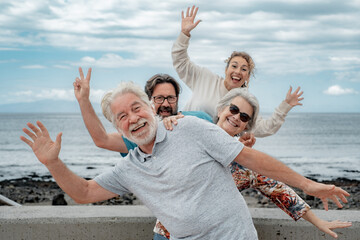 Playful multi generation family having fun together on outdoor excursion at the seaside, gesturing towards the camera. Parents, son and daughter-in-law enjoying free time and recreational activities - Powered by Adobe