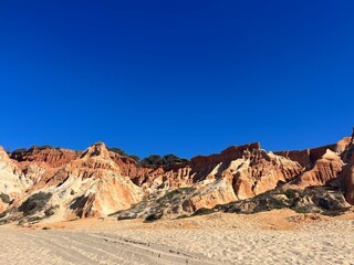 Orange and white rocky ocean coast, rock, blue sky, ocean bay