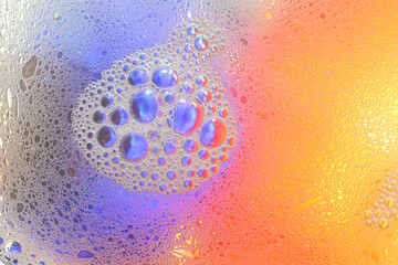 Macro shot of water-oil emulsion over colored background
