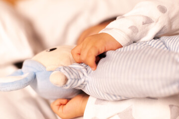 Obraz na płótnie Canvas baby's hands holding doll while sleeping
