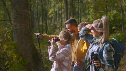 Smiling family of four enjoying hiking in trough forest.