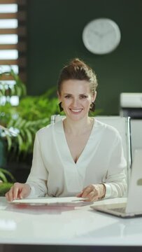 Time to move on. smiling young woman realtor in modern green office in white blouse with home for sale sign.