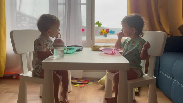 baby group eating at the table in kindergarten. happy family kid dream concept. baby twins learning to eat sitting at the table near the window eating. lifestyle baby group kindergarten breakfast