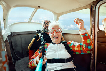 Senior woman skydiving with instructor in airplane