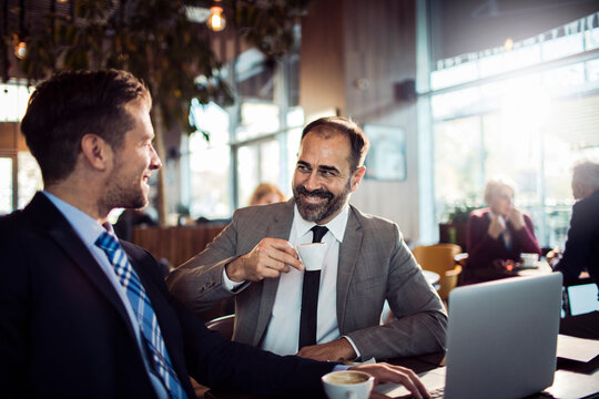 Two Young Businessmen Drinking Coffee In Cafe