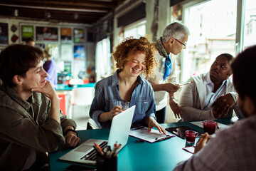 Multigenerational and diverse group of people working on a project together in a startup company office