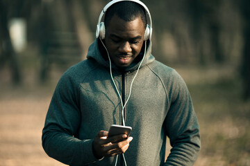Focused jogger selecting music on his smartphone before a run
