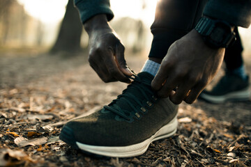Runner tying his shoelaces getting ready for a jog in the park - obrazy, fototapety, plakaty