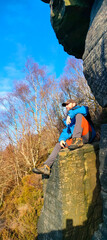 View of a man seated on a rock boulder from low angle view in a sunny winter day