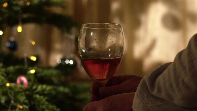 Woman relaxing with glass of red wine in front of Christmas tree