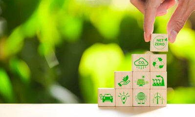 Carbon footprint concept. Hand put wooden cube with net zero icon and green icon on nature...