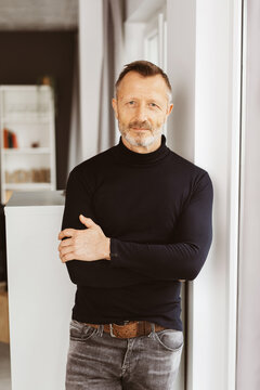 Confident Bestager Man in Stylish Black Turtleneck, Arms Crossed, Gazing into the Camera with Modern Elegance