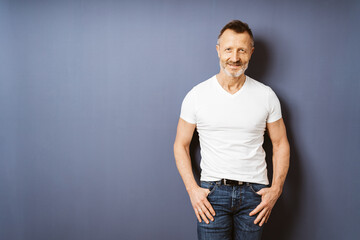 Active Aging: Sporty Bestager Man in White T-Shirt Smiling Against Blue Wall with Copyspace