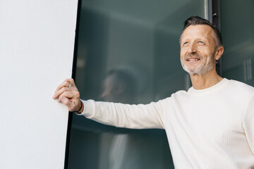 Confident Bestager Leaning on Glass Wall, Gazing Ahead with Graceful Serenity in Urban Lifestyle