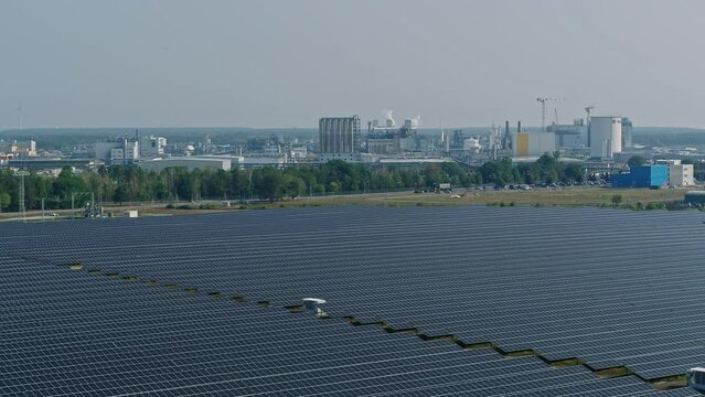 Drone flight over a large solar field with the BASF chemical plant in the background. drone move to the right.
