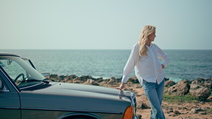 Fototapeta premium Stylish model posing retro car at summer seacoast. Woman standing sunny beach.