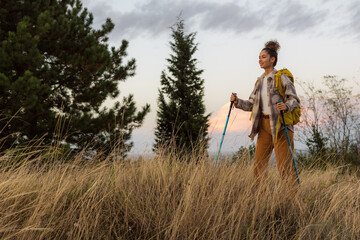 A beautiful hiker in golden sunset, wandering off-trail through dry grasslands and rustic meadows.