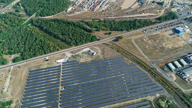 Drone flight over a large solar field with the BASF chemical plant in the background. Drone looks 90 degrees downwards top shot