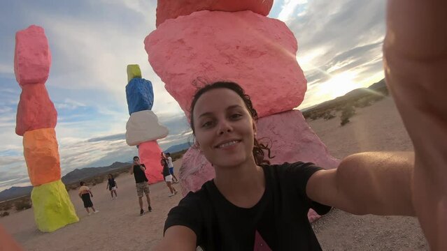 Female smiling tourist visiting the Seven Magic Mountains, a colorful stacked rocks sculpture in the desert near Las Vegas