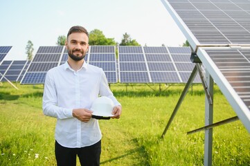 man in white shirt standing near photovoltaic panels on sunny day in countryside