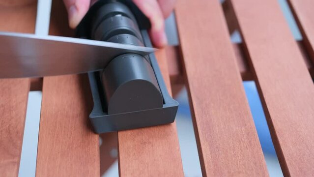 sharpen knives with home knife sharpening tool on wooden table	
