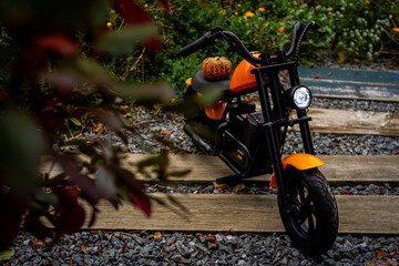 An orange children's eBike, styled like a motorcycle, adorned with a whimsical pumpkin, symbolizing...