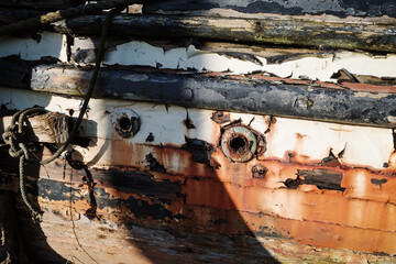 side of a old wooden hulled boat flaking paint rust marks and rotten timbers