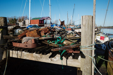 Fototapeta na wymiar Wooden boat mooring with piles of old junk on the jetty Skippool creek Lancashire UK