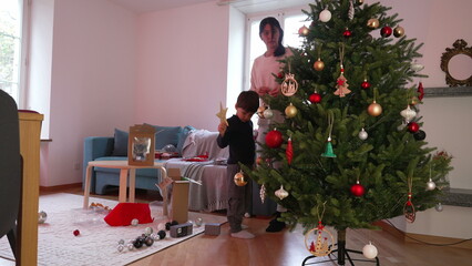 Candid Family Scene, Preparing for Christmas in Living Room - Mother and Child Decorating Tree