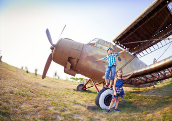 Little boy and little girl pilot near the retro airplane