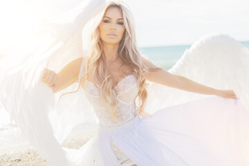 beautiful girl with angel wings is walking along the seashore