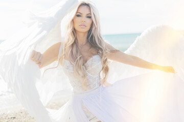 Fototapeta na wymiar beautiful girl with angel wings is walking along the seashore