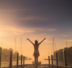 Fototapeta premium Happy woman walking down dock with arms outstretched