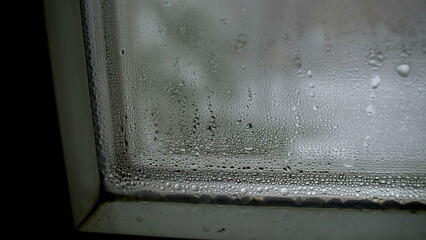 Condensation on glass during cold weather, winter season manifestation of droplets in macro closeup in window