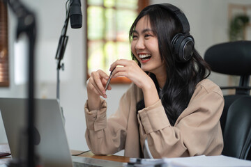 Woman host in headphone use laptop with microphone to talking and recording audio podcast in studio