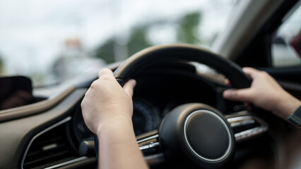 Close up hands of driver holding steering wheel in car, road trip, driving on local road
