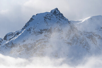 Obraz premium Mountain covered with snow and fog. Alpine landscape in Italy, Europe. Snow-capped mountains