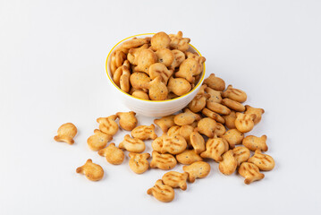 Whie bowl full of fish-shaped crispy snacks isolated on white background