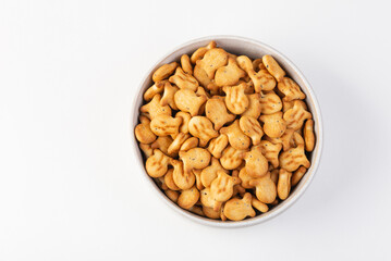 Top view of fish-shaped crackers in white plate isolated on white background