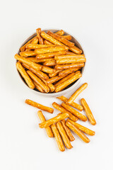 Top view of salty mini breadsticks on white  plate isolated on white background