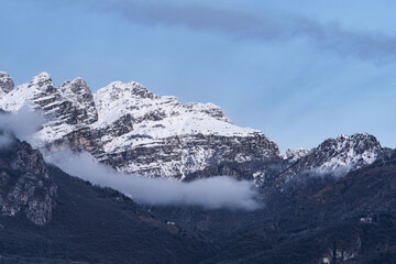 Mountain covered with snow and fog. Alpine landscape in Italy, Europe. Snow-capped mountains against blue sky