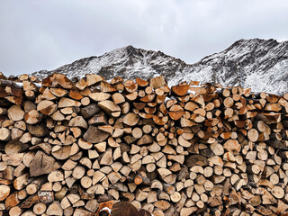 stack of firewood. a pile of wood with snowy mountain. big woodpile with large logs cut by loggers...