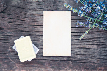 Sheet of paper in composition with bouquet of fresh lavender on old wooden desk